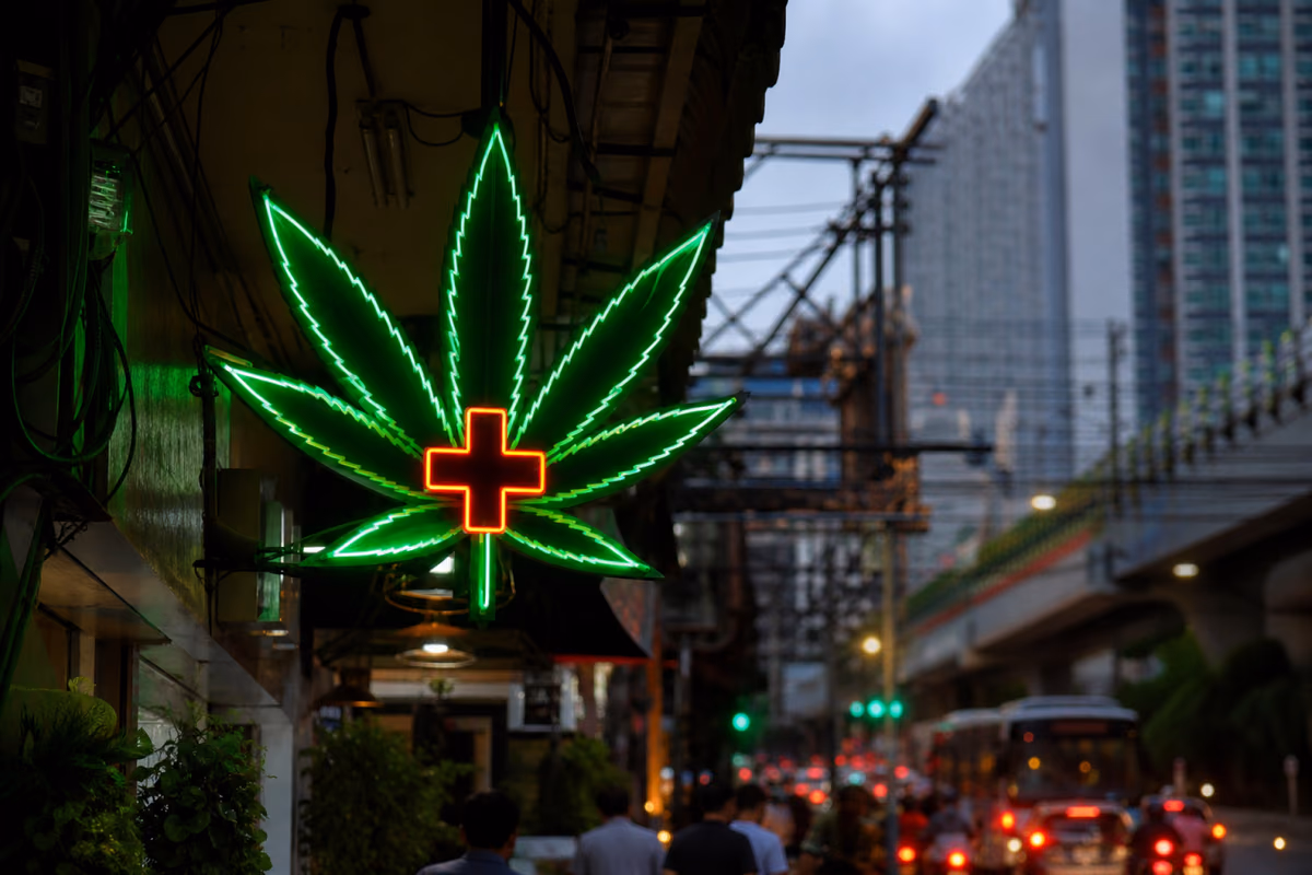Letrero de neón con hoja de cannabis y cruz médica sobre una concurrida calle de Bangkok en Tailandia